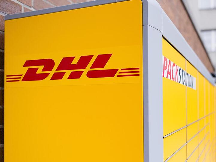 Ein Arbeiter baut eine Packstation von Deutsche Post DHL auf.