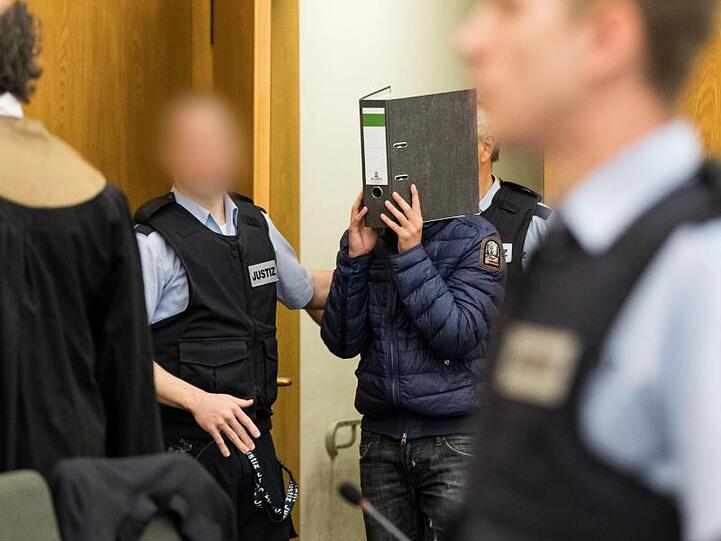 Einer der Angeklagten kommt in den Gerichtssaal.