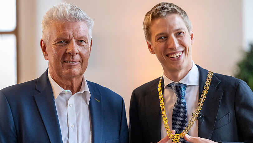 Der neue M&uuml;nchner Oberb&uuml;rgermeister Dominik Krause (r, Gr&uuml;ne) steht w&auml;hrend seiner Amtseinf&uuml;hrung im Gro&szlig;en Sitzungssaal des Rathauses neben seinem Amtsvorg&auml;nger Dieter Reiter (l). In der Hand h&auml;lt er seine Amtskette.
