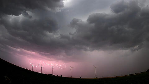 Eine Unwetterfront mit Blitzen, Starkregen und Sturmböen zieht über Windräder bei Sehnde in der Region Hannover hinweg.