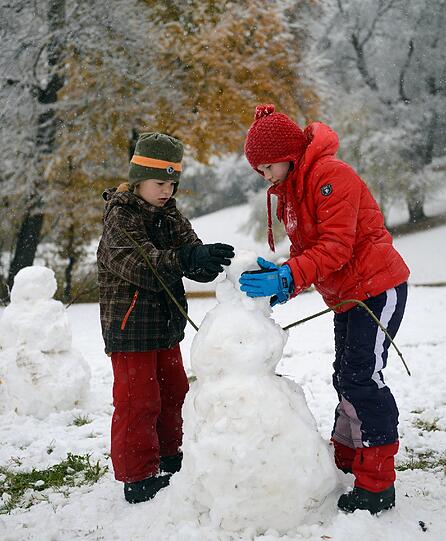Pünktlich zum Wochenende ist der erste Schnee da! In Weimar (Thüringen) bauen Kinder begeistert an ihrem Schneemann.