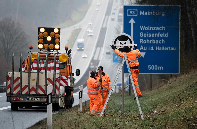 Auf der A9 und der A93 rund um das Autobahndreieck Holledau stellen Mitarbeiter der Autobahnmeisterei Schilder für automatisch fahrende Autos am Fahrbahnrand auf.
