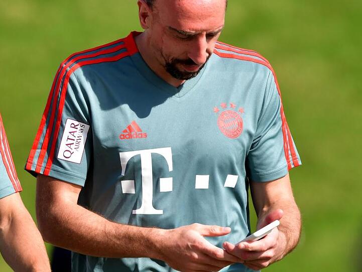 Franck Ribéry geht mit dem Mobiltelefon in der Hand vor Beginn einer Übungseinheit am Vormittag über den Platz. Foto: Peter Kneffel