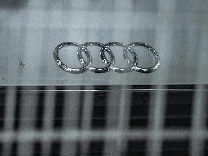 Hinter einem Metallzaun steht ein Audi mit dem Logo des Autoherstellers auf der Motorhaube in einem Parkhaus. Foto: Armin Weigel/Archivbild