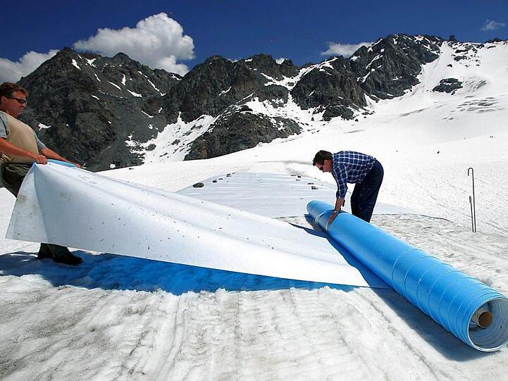 Retten, was zu retten ist: Helfer rollen im Hochsommer schützende Planen auf dem Tortin-Gletscher in der Schweiz aus.