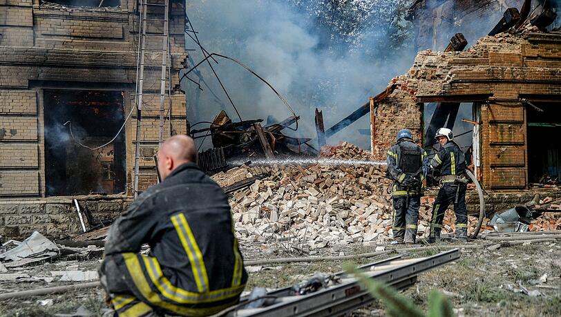 Ein Feuerwehrmann macht eine Verschnaufpause, während zwei seiner Kollegen vor einem zerstörten Gebäude der Chemisch-Mechanischen Hochschule in Slowjansk ein Feuer löschen. Ein Feuerwehrmann macht eine Verschnaufpause, während zwei seiner Kollegen vor einem zerstörten Gebäude der Chemisch-Mechanischen Hochschule in Slowjansk ein Feuer löschen.