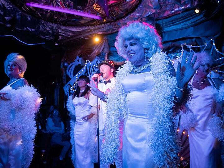 Mehrere Travestiekünstler stehen im Travestietheater "Paradies" bei einer Show auf der Bühne. Foto: Daniel Karmann/Archiv