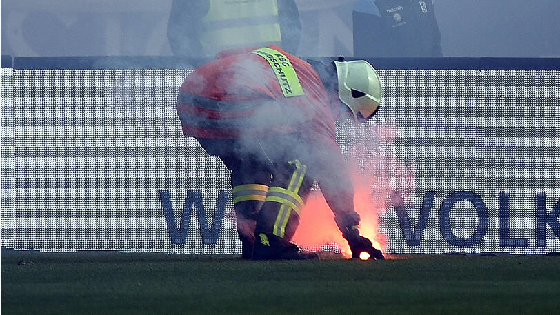 Ein Feuerwehrmann schafft ein Bengalo vom Rasen.