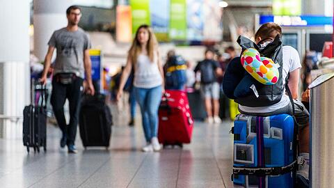 Ein junger Mann ruht sich auf seinem Koffer im Frankfurter Flughafen aus.