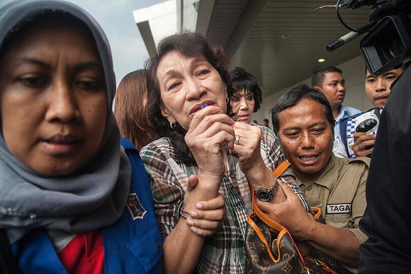 Die Angehörigen der Passagiere von Flug QZ8501 müssen von Helfern gestützt werden