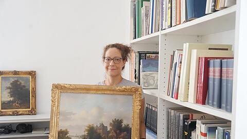Christiane Pelikan, eine Mitarbeiterin des Auktionshauses, zeigt eines der Gemälde, die versteigert werden.