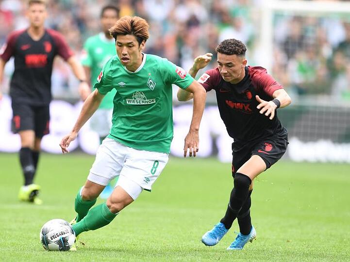 Werders Yuya Osako (l) setzt sich gegen Augsburgs Ruben Vargas durch.
