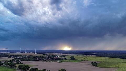 Dunkle Regenwolken ziehen über eine Landschaft. Foto: Patrick Pleul/Archivbild