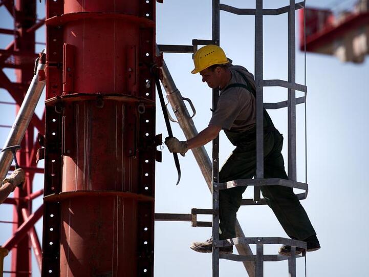 Ein Arbeiter montiert an einem Kran. Foto: Alexander Heinl/Archivbild