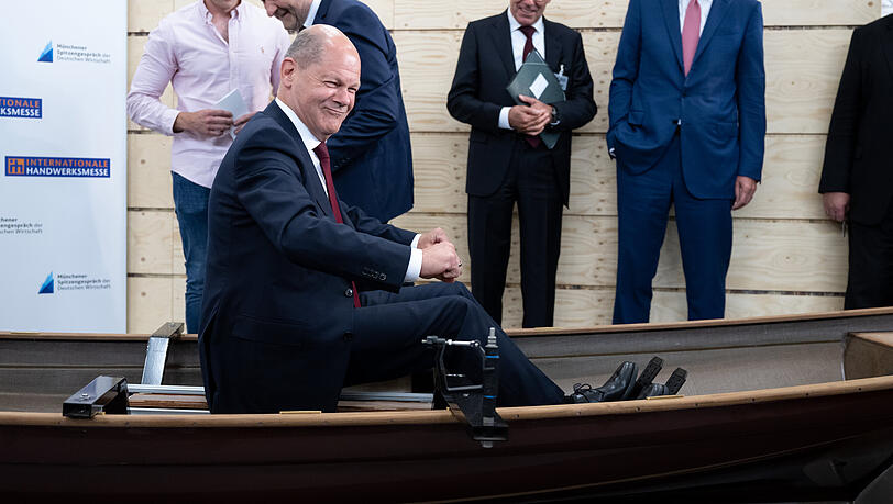 Bundeskanzler Olaf Scholz (SPD) sitzt bei einem Rundgang über die Internationale Handwerksmesse (IHM) am Messestand der Firma Baumgarten Bootsbau in einem Boot. Scholz und Vertreter der Wirtschaft trafen sich im Rahmen der Internationalen Handwerksmesse IHM.