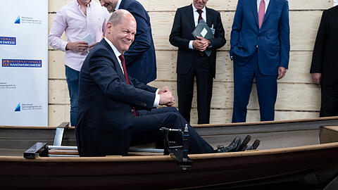 Bundeskanzler Olaf Scholz (SPD) sitzt bei einem Rundgang über die Internationale Handwerksmesse (IHM) am Messestand der Firma Baumgarten Bootsbau in einem Boot. Scholz und Vertreter der Wirtschaft trafen sich im Rahmen der Internationalen Handwerksmesse IHM.