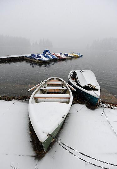 Mit Schnee bedeckt sind am Samstag Boote, am Spitzingsee liegen.