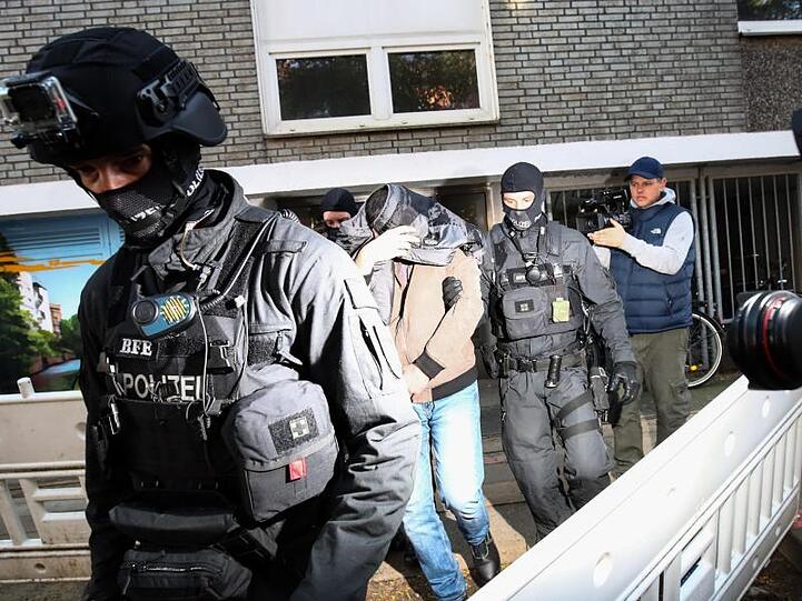 Terror-Razzia in Hamburg: Ein Mann wird von Polizisten aus einem Haus geführt.