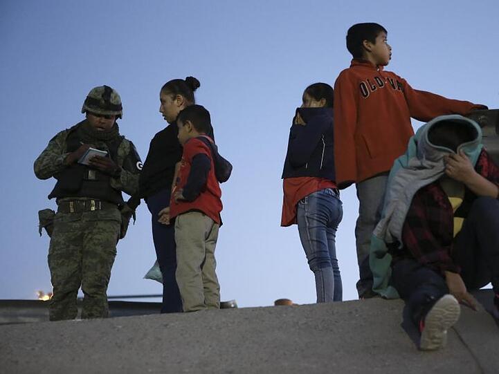 Ein Militärpolizist (l.) mit dem Abzeichen der neuen Nationalgarde hält guatemaltekische Migranten fest, um sie daran zu hindern, von Ciudad Juarez nach El Paso in Texas zu gelangen.
