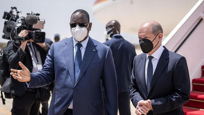 Bundeskanzler Olaf Scholz (r, SPD), wird von Macky Sall, Präsident der Republik Senegal mit militärischen Ehren am Flughafen begrüßt.