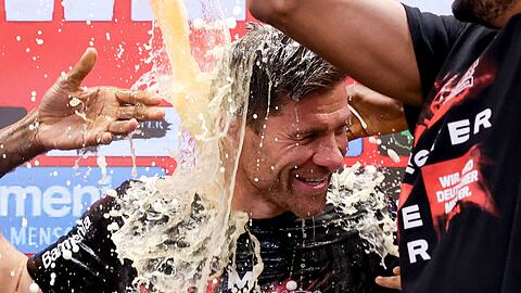 Fußball: Leverkusens Trainer Xabi Alonso wird bei der Pressekonferenz nach dem Spiel von seinen Spielern mit Bier übergossen. Leverkusen gewinnt die Deutsche Meisterschaft.