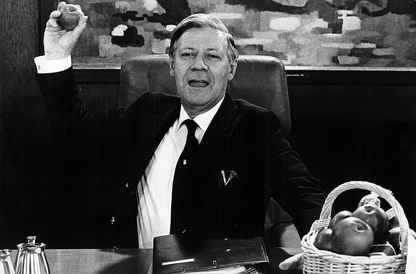 19.12.1979: Helmut Schmidt zielt zu Beginn der Kabinettssitzung in Bonn mit einem Apfel auf die Kabinettsmitglieder.