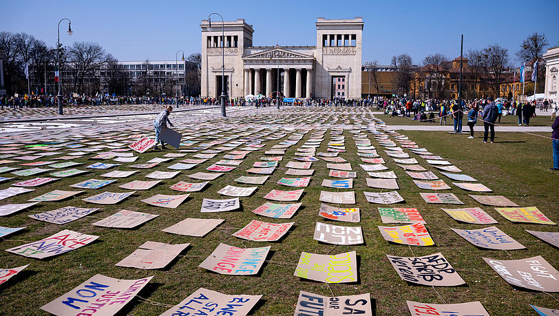 Zahlreiche Menschen nehmen an einer Demonstration zum globalen Klimastreik teil und haben Plakate mit ihren Forderungen auf den Königsplatz gelegt.