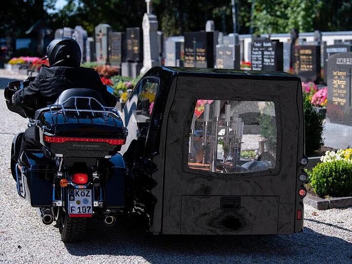 Bestatter Wolfgang Frisch fährt mit seinem Bestattungsmotorrad, einer umgebauten Harley-Davidson, über einen Friedhof. Foto: Sven Hoppe