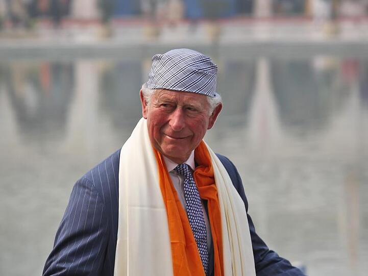 Der britische Prinz Charles mit landestypischer Kopfbedeckung und Schal.