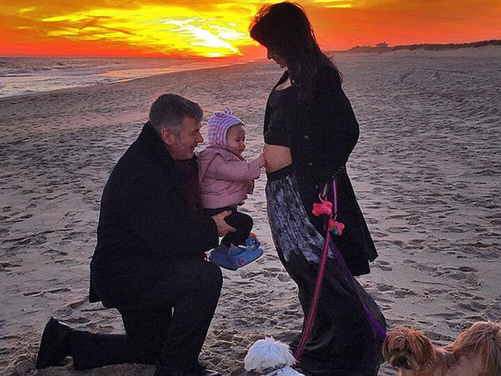 Familienglück am Strand: Alec Baldwin mit Tochter Carmen, die den Bauch der schwangeren Mutter streichelt