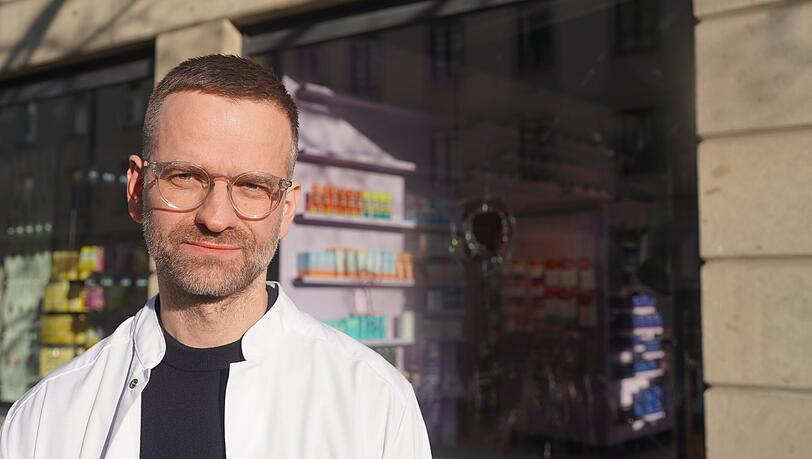 Fabian Ortner leitet die Apotheke am Ostbahnhof. Hinter ihm ist das kaputte Schaufenster zu sehen. Zum vierten Mal wurde hier die Scheibe eingeschlagen. "Man f&uuml;hlt sich machtlos", sagt er zur AZ.