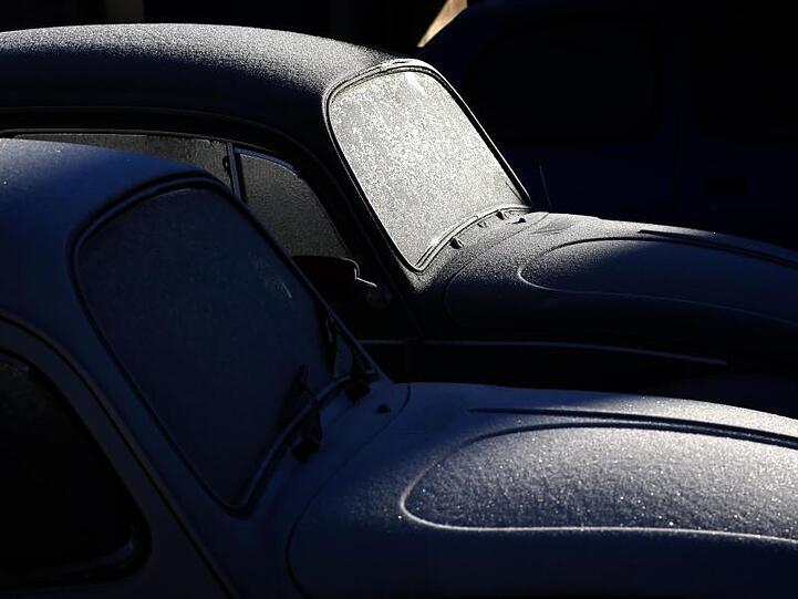 Zwei mit Eiskristallen überzogene VW-Käfer glitzern im Sonnenschein.
