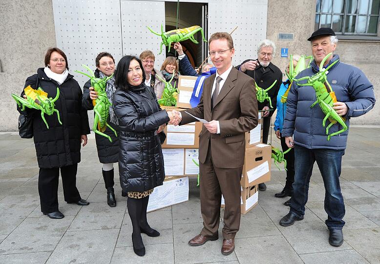 Grüne Plastik-Heuschrecken als Warnung: Ministerialrat Horst Wonka nimmt die Unterschriften vor der Staatskanzlei entgegen.