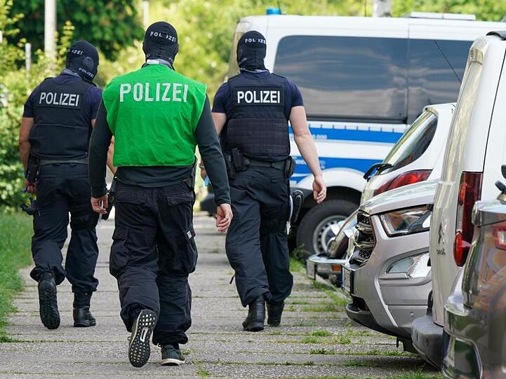 Bundespolizisten laufen vor einem Haus in Leipzig Grünau entlang.
