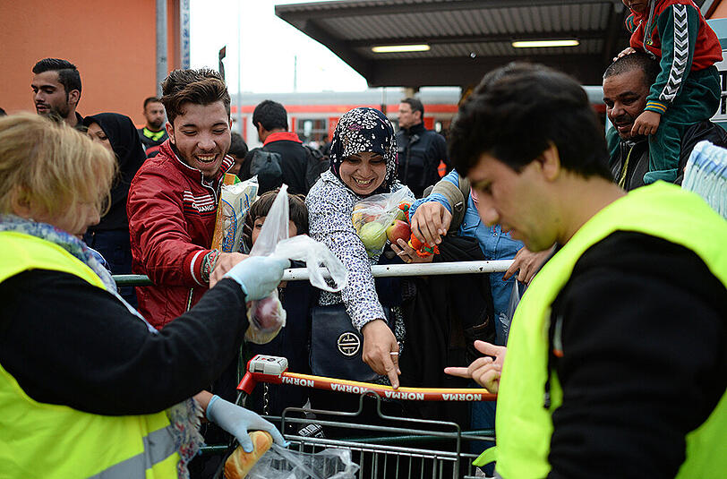 Helfer verteilen am Bahnhof Freilassing Lebensmittelspenden an ankommende Flüchtlinge.