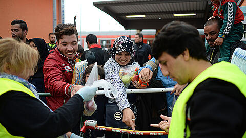 Helfer verteilen am Bahnhof Freilassing Lebensmittelspenden an ankommende Flüchtlinge.