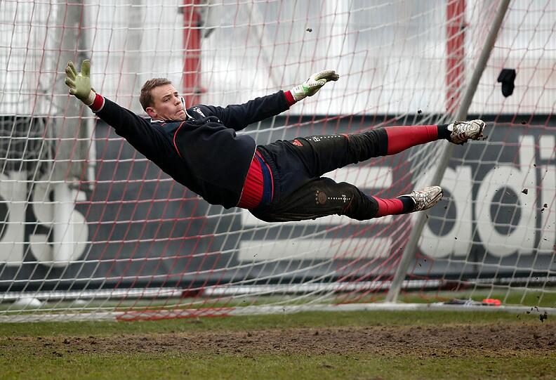Und springt und streckt sich noch bevor der Ball ihn erreicht.