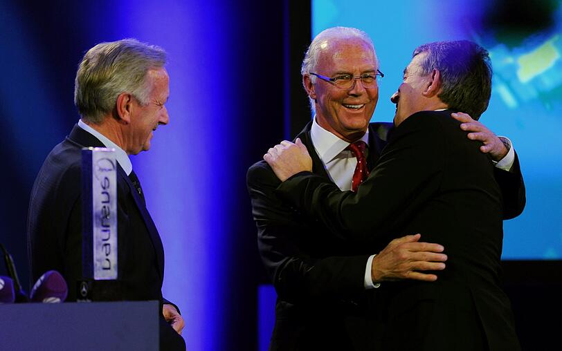 Der DFB-Präsident Wolfgang Niersbach (r-l) umarmt den Ehrenpräsident des FC Bayern München, Franz Beckenbauer, unter den Blicken des Mercedes-Benz-Marketing- und Vertriebsvorstands Joachim Schmidt. Niersbach wurde mit dem "Laureus Medien Ehrenpreis für Wohltätigkeit" ausgezeichnet.