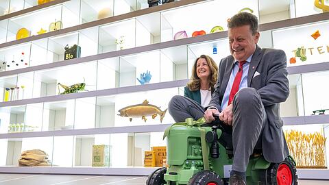 Wolfang Heckl, Generaldirektor des Deutschen Museum, sitzt während der Eröffnung der ersten neuen Dauerausstellung „Landwirtschaft und Ernährung“, die im Deutschen Museum präsentiert wird, auf einem Spielzeug-Traktor. Hinter ihm lacht Maria Thon, Geschäftsführerin der BayWa Stiftung. Das Museum wird seit geraumer Zeit saniert.