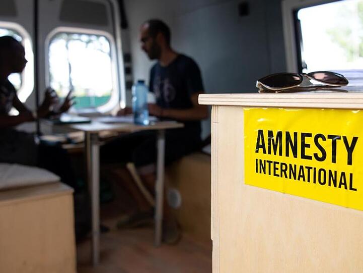 Aydin Alinejad vom Münchner Flüchtlingsrat unterhält sich in dem Infobus für Flüchtlinge mit einer Frau aus Uganda.