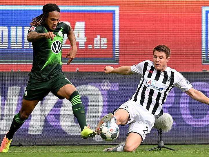 Wolfsburgs Kevin Mbabu (l) im Duell mit Dominique Heintz vom SC Freiburg.