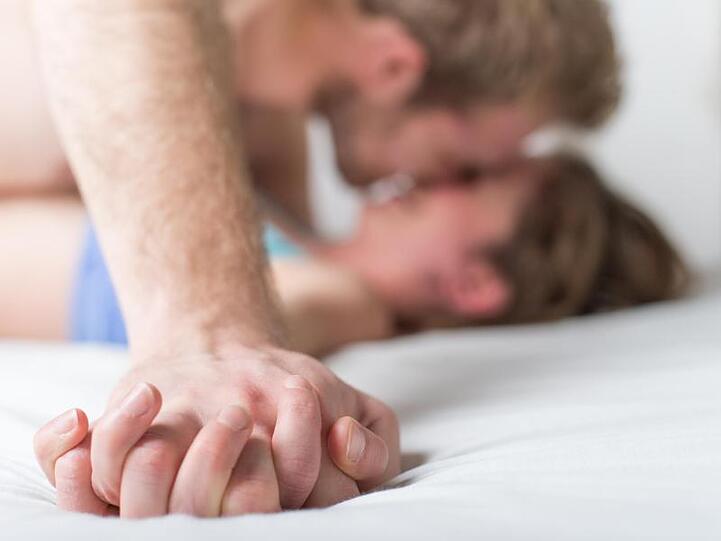 Ein Paar liegt im Bett. Foto: Christophe Gateau/dpa/Illustration
