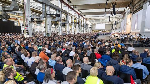 Tausende Mitarbeiterinnen und Mitarbeiter folgen der Versammlung in Halle 11 des Stammwerks. Tausende Mitarbeiterinnen und Mitarbeiter folgen der Versammlung in Halle 11 des Stammwerks.