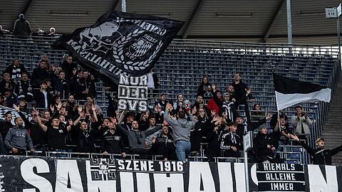 Fans aus Sandhausen stehen mit Flaggen auf der Tribüne.