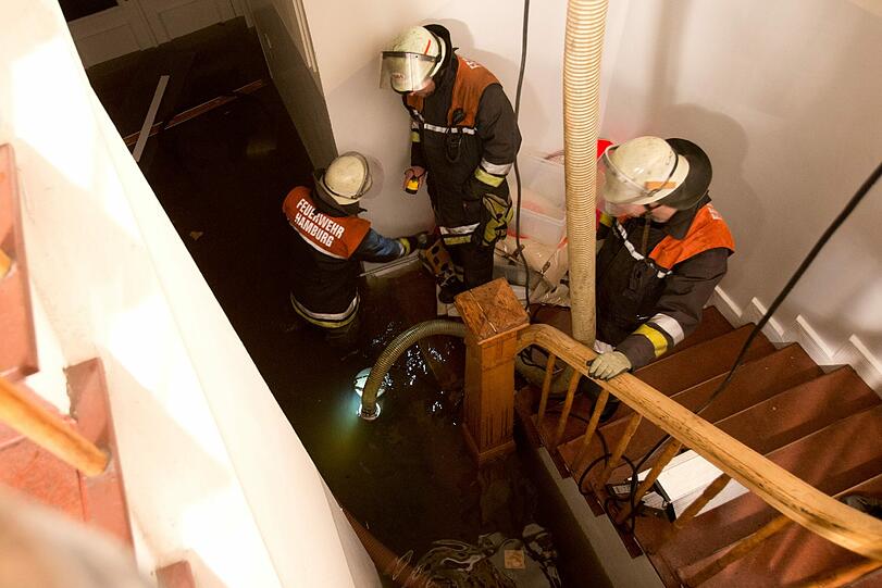 Einsatzkräfte der Feuerwehr pumpen in Hamburg ein überschwemmtes Ladengeschäft leer