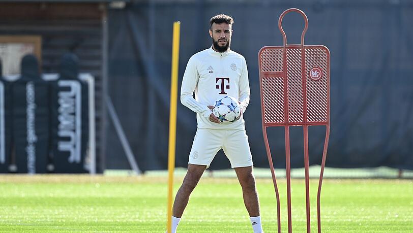 Noussair Mazraoui hält während einer Trainingseinheit des FC Bayern München einen Ball in der Hand.