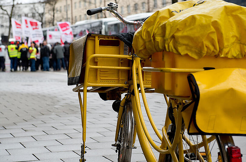 Ein Postfahrrad steht bei einem Warnstreik der Mitarbeiter der Deutschen Post vor einer Postfiliale in München. Der Dauer-Streik bei der Deutschen Post wird für viele Verbraucher zur Geduldsprobe.