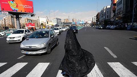 Eine Frau &uuml;berquert eine Kreuzung in der Innenstadt von Teheran. (Archivbild)
