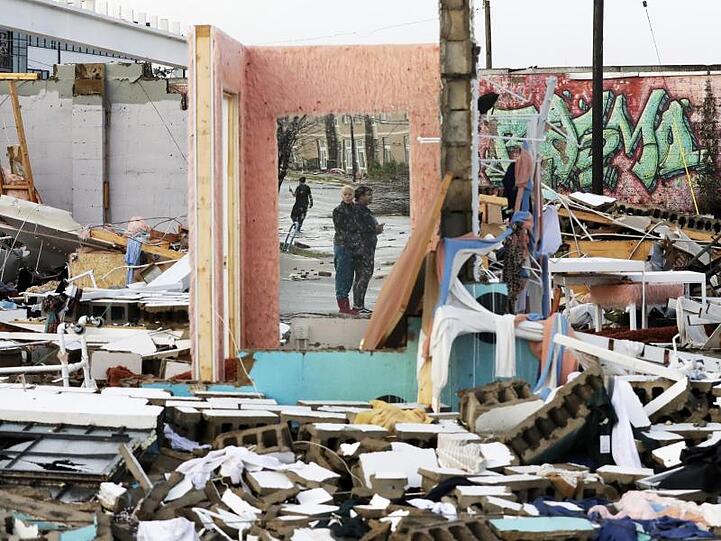 Menschen sind in Nashville in einem Spiegel zu sehen, der an einer Wand eines zerstörten Hauses hängt.