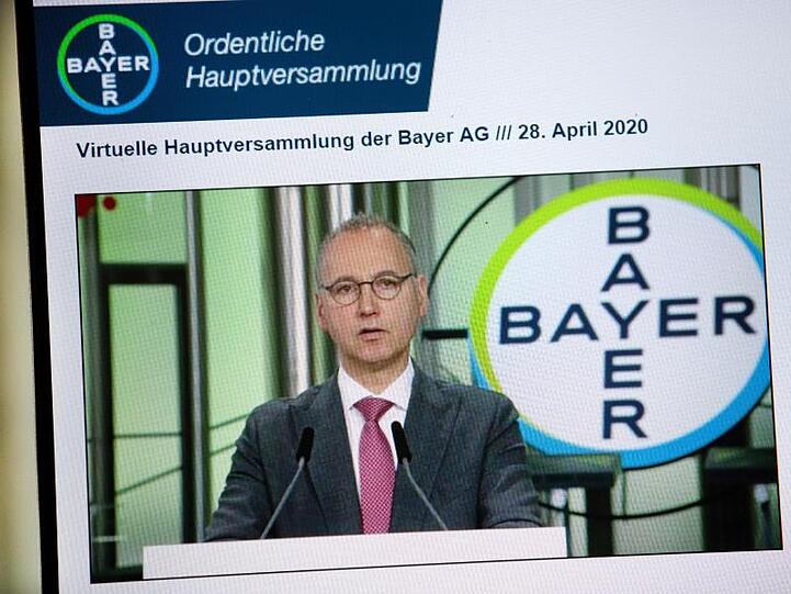 Auf einem Bildschirm ist Bayer Konzernchef Werner Baumann bei seiner Rede zu sehen.